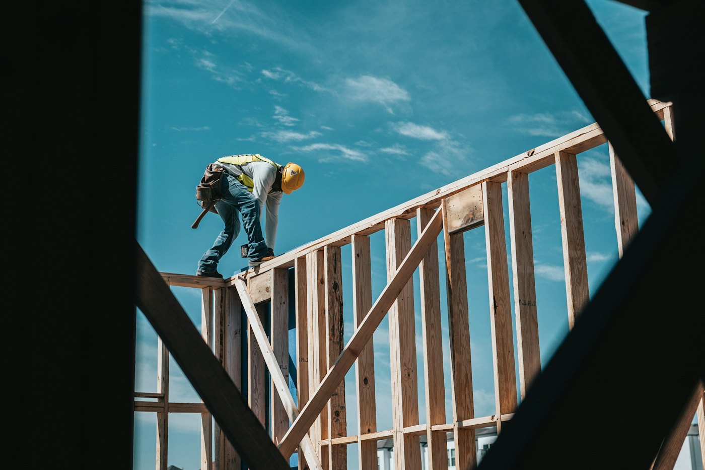 Carpenter standing on new wall framing against a blue sky